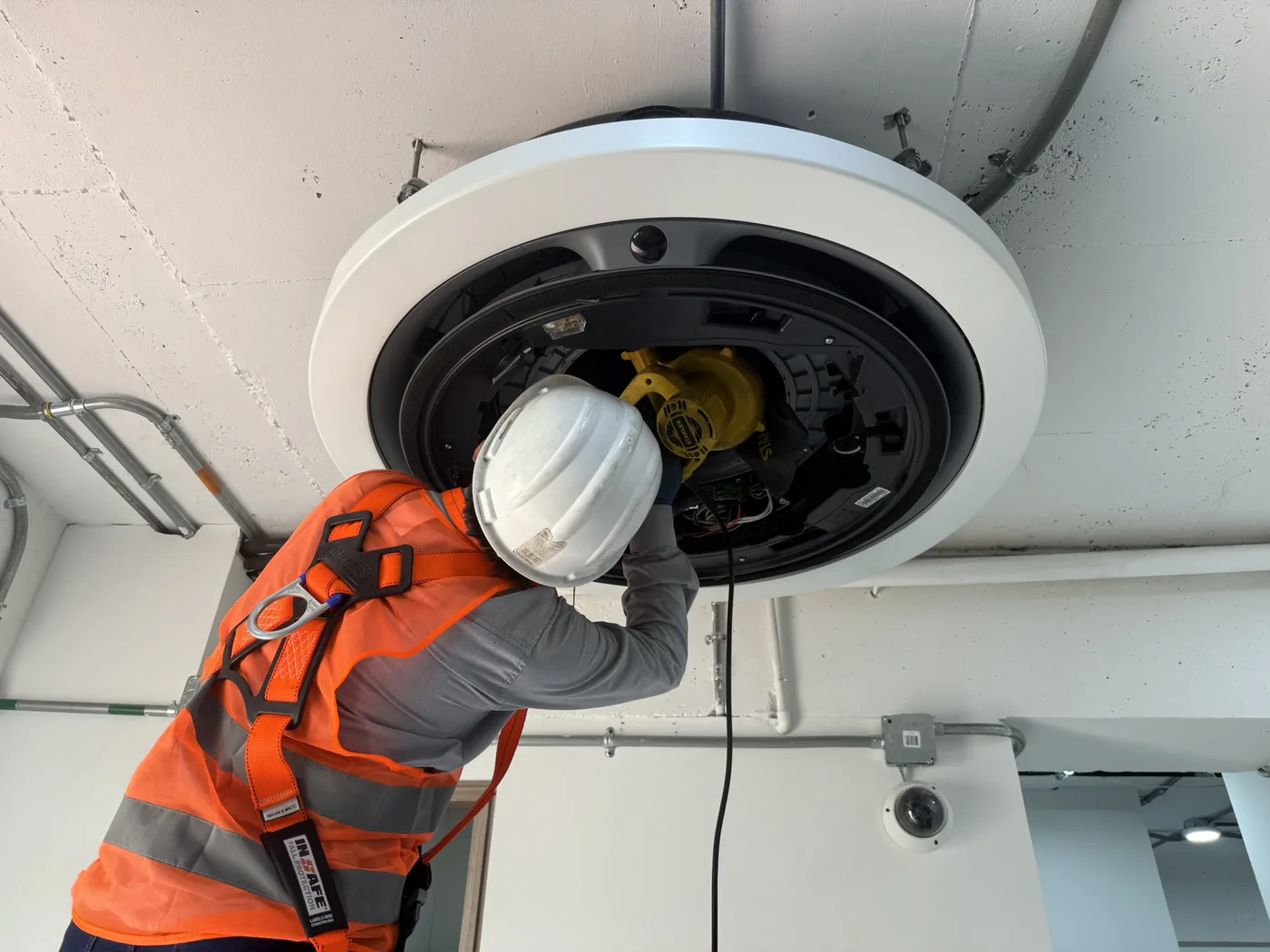 Técnico con casco y arnés de seguridad trabajando en un equipo de techo